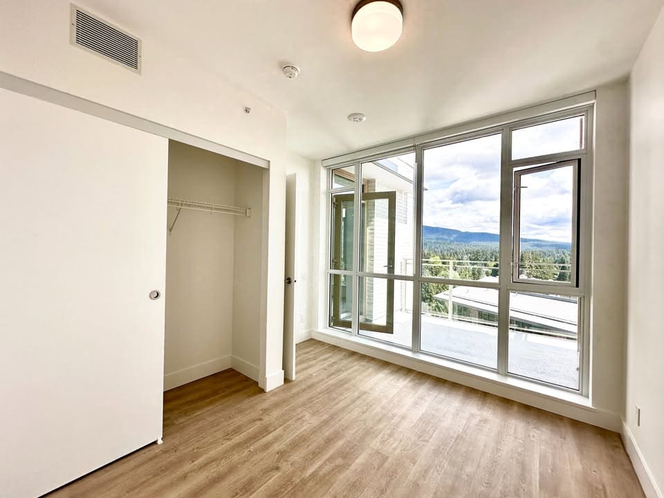 Bright bedroom with large windows and a walk-in closet, showcasing modern interior design and scenic mountain views in a Vancouver-area home listed by Orca Realty Inc.