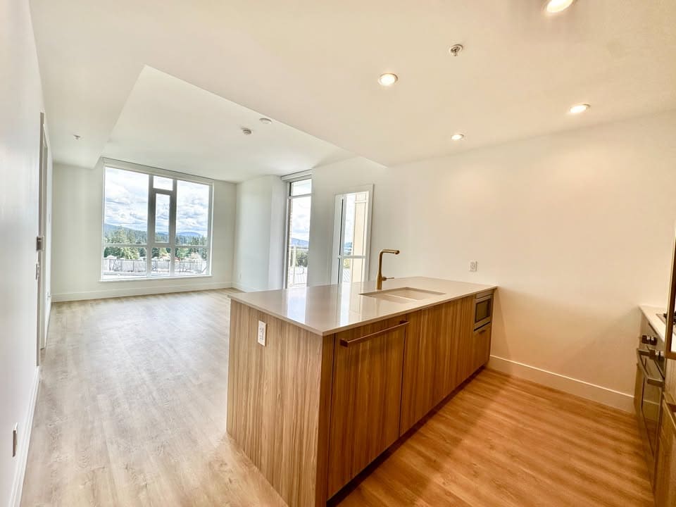 Bright modern open-concept living space with large windows and a contemporary kitchen, perfect for Vancouver Island real estate buyers.