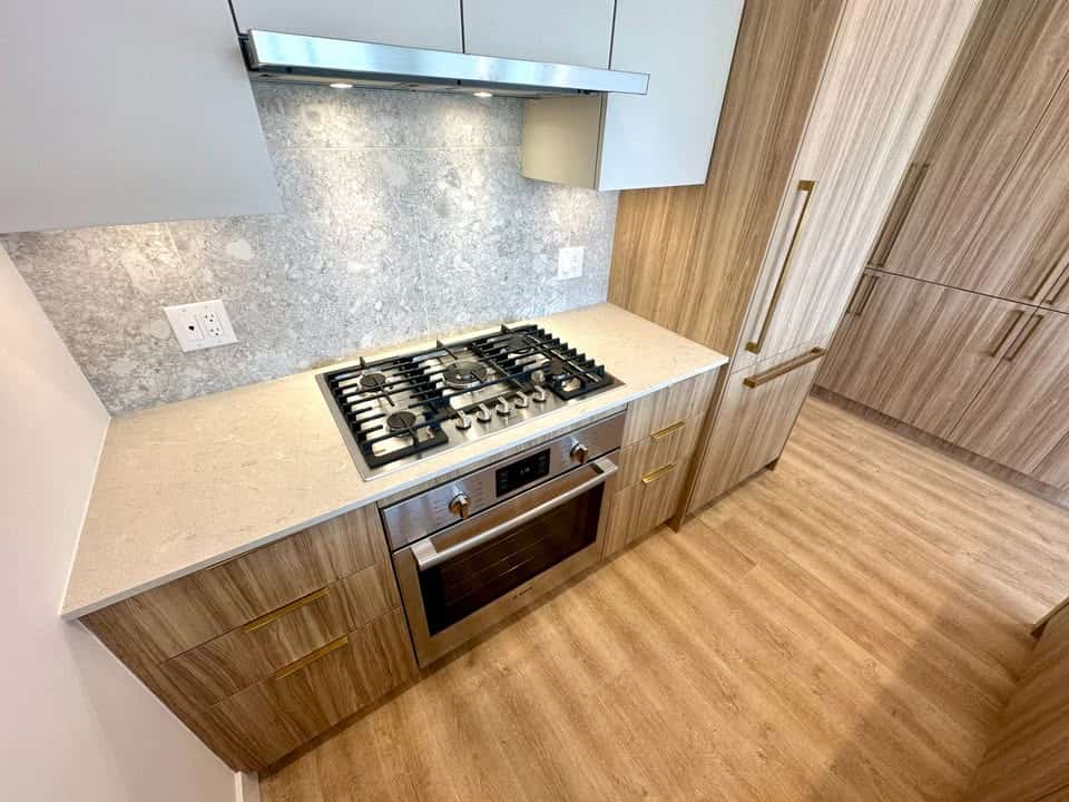 Modern kitchen with built-in gas stove and oven, wood cabinetry, granite backsplash, and ample storage space, ideal for Vancouver real estate and property listings.