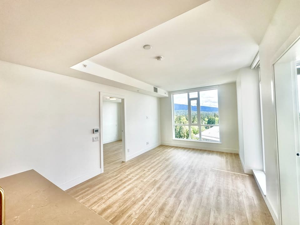 Bright, modern living room with large windows showcasing scenic mountain views in a Vancouver-area property listed by Orca Realty Inc.