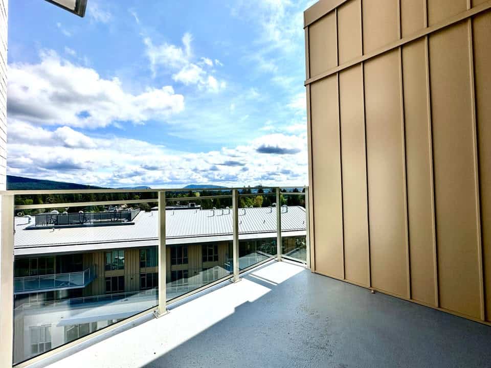 Modern balcony with glass railing and scenic mountain view in a Vancouver-area condo. Perfect for enjoying panoramic vistas and outdoor relaxation.