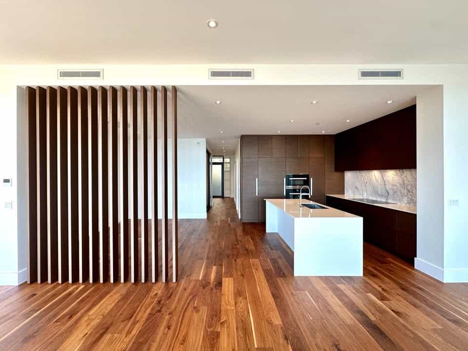 Contemporary open-plan kitchen with wooden accents, white island, marble backsplash, and modern cabinetry, showcasing luxury real estate in Vancouver by Orca Realty Inc.