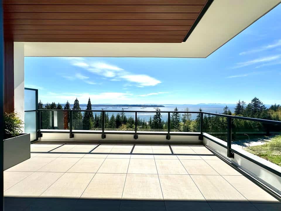 Stunning balcony view overlooking a lush forest and waterway, featuring modern design and glass railing, perfect for enjoying Vancouver Island’s scenic landscape.