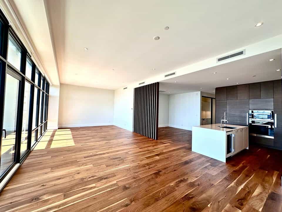 Spacious modern open-concept living area with large floor-to-ceiling windows, hardwood flooring, and contemporary kitchen in a luxury property listed by Orca Realty Inc.