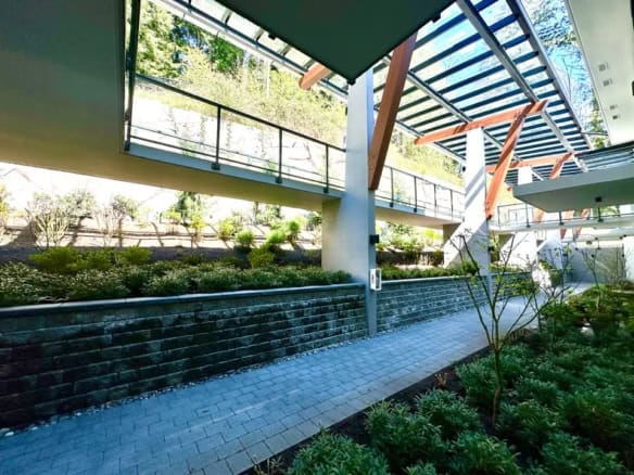 Modern commercial building exterior with glass and steel architectural design, lush landscaping, and natural light, ideal for Vancouver-area real estate and property investment.