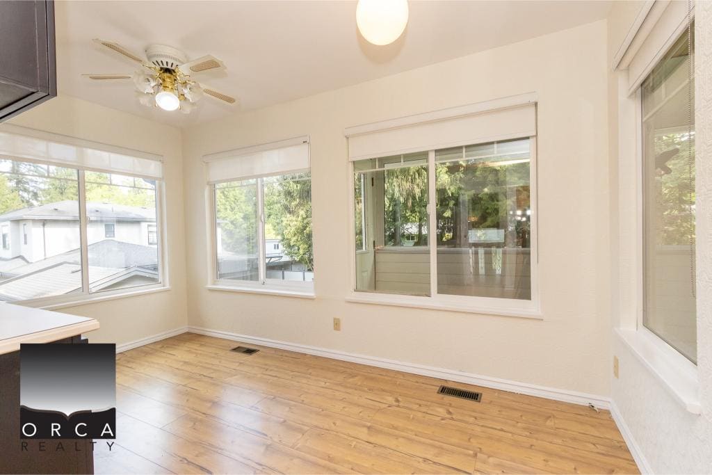 Bright sunlit room with multiple large windows, hardwood flooring, and neutral walls, ideal for home staging or future homebuyers.