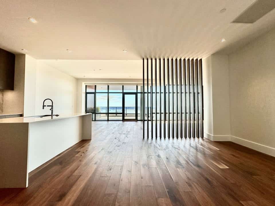 Spacious modern condo interior with open floor plan, large windows with ocean views, hardwood flooring, and contemporary design, ideal for Vancouver real estate buyers.