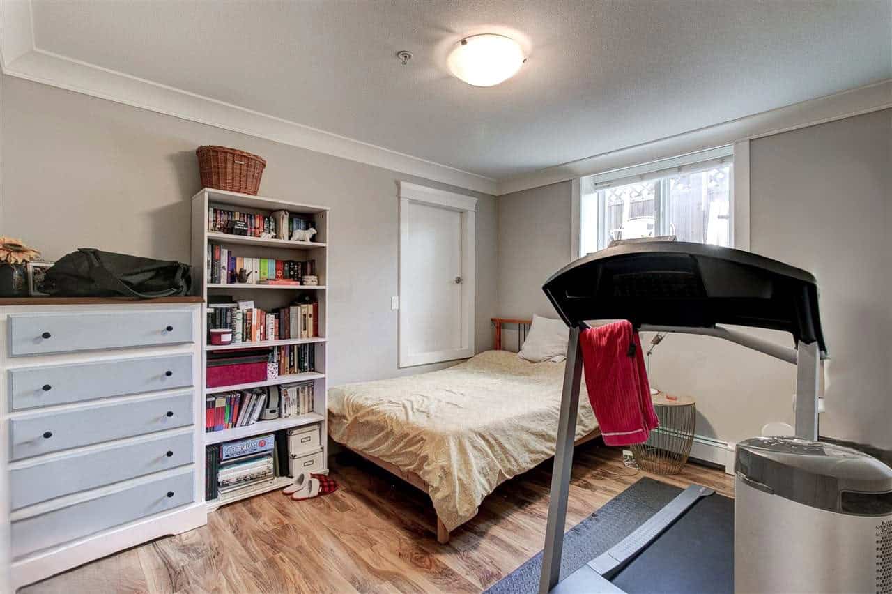 Cozy bedroom with a bed, bookshelf, and treadmill, ideal for home living and fitness. Bright natural light from window enhances space comfort, perfect for families or individuals seeking a versatile room.