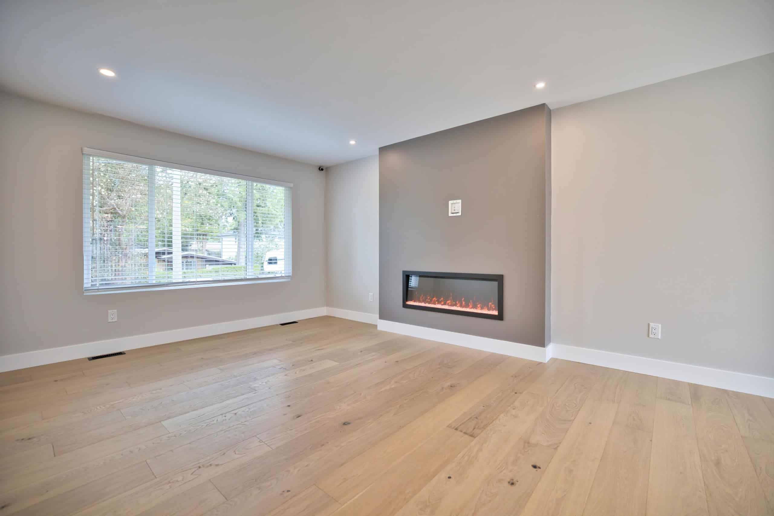 Modern living room with large window, sleek electric fireplace, and hardwood flooring, ideal for real estate listings in Vancouver, showcasing property features by Orca Realty Inc.