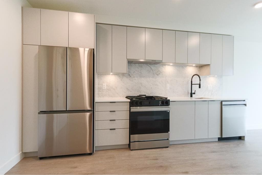 Stainless steel refrigerator and modern kitchen cabinetry in a contemporary home, showcasing sleek appliances and minimalist design.