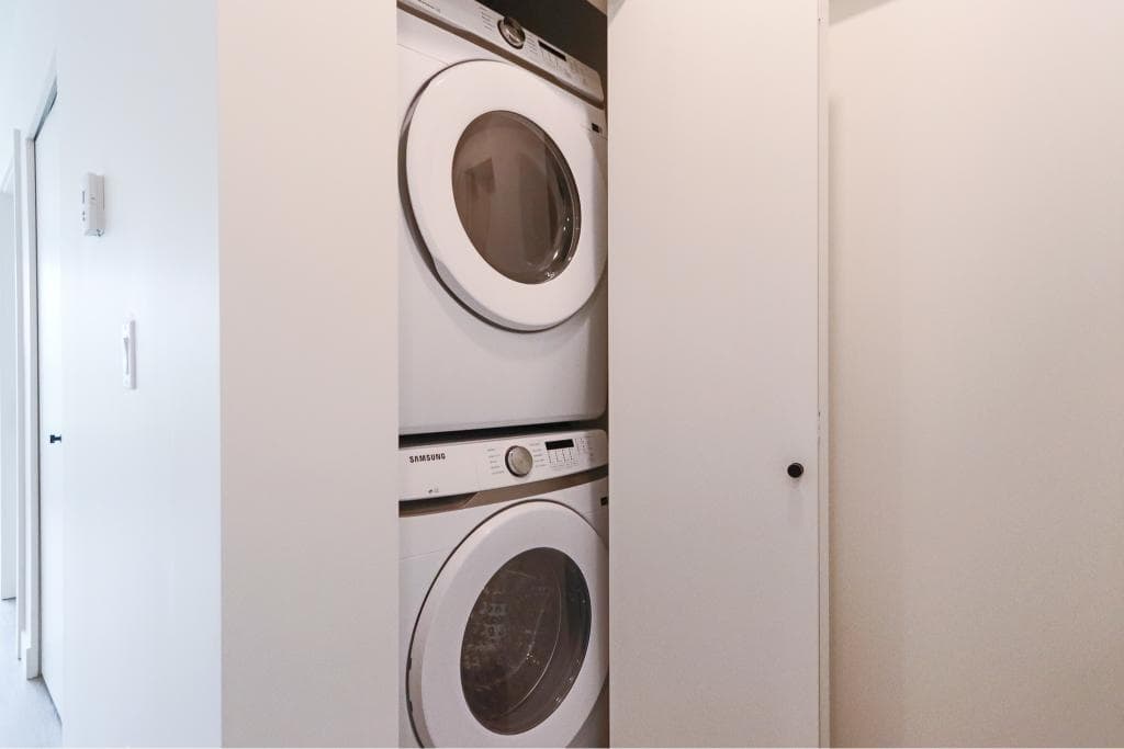 Stacked washer and dryer in a laundry closet at Orca Realty Inc., showing modern appliances in a clean, organized space for efficient home living in Canada.
