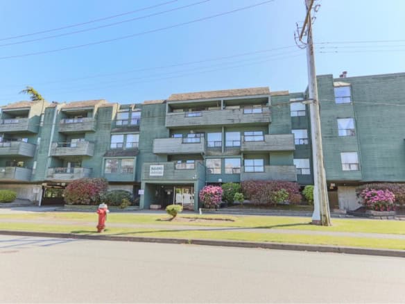 Spacious multi-unit apartment building with balconies, landscaped gardens, and parking in a residential area, ideal for real estate investment and rentals in Vancouver, BC.