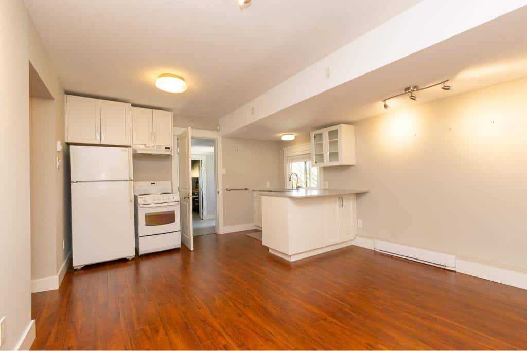 Bright open-concept kitchen and living space in Victoria, BC. Modern white cabinetry, hardwood floors, and ample natural light make this ideal for homebuyers seeking comfort and style.