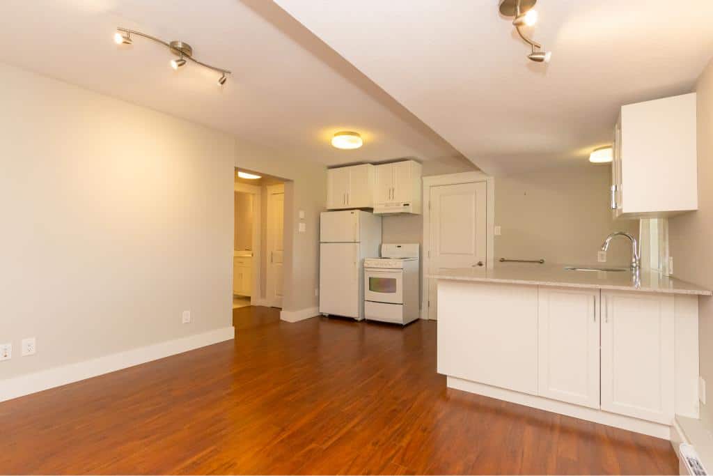 Bright and open real estate listing interior view in Vancouver, showcasing modern kitchen with white cabinetry, hardwood floors, and ample natural light, perfect for homebuyers.