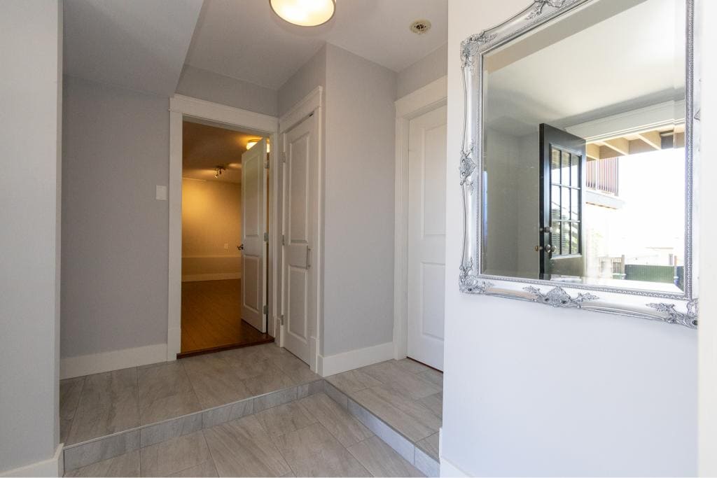 Bright entrance hallway with white walls, decorative mirror, and access to indoor spaces, showcasing modern home design in Victoria BC. Perfect for homebuyers seeking elegant, inviting interiors.