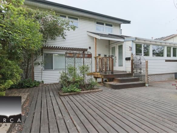 Spacious backyard deck with wooden stairs and garden beds, perfect for outdoor living and entertaining, featured by Orca Realty Inc. Canada.