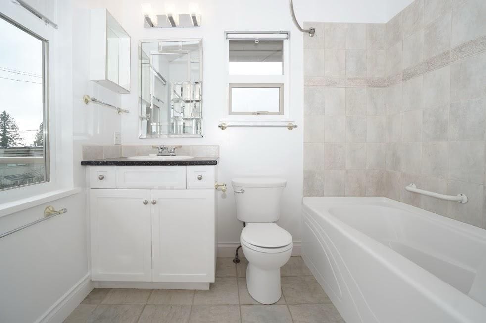Bright and clean bathroom with modern fixtures, bathtub, and vanity, ideal for Vancouver homes. Featuring white walls, tiled accents, and natural light, perfect for comfortable living.