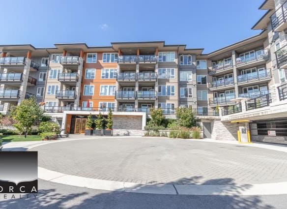 Contemporary multi-story residential apartment building with modern architecture, spacious balconies, and lush landscaping, located in a vibrant urban community in Vancouver.