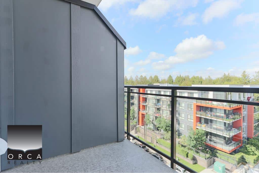 Contemporary balcony view of modern residential apartments with glass railings and lush greenery, showcasing luxury condo living in Vancouver.