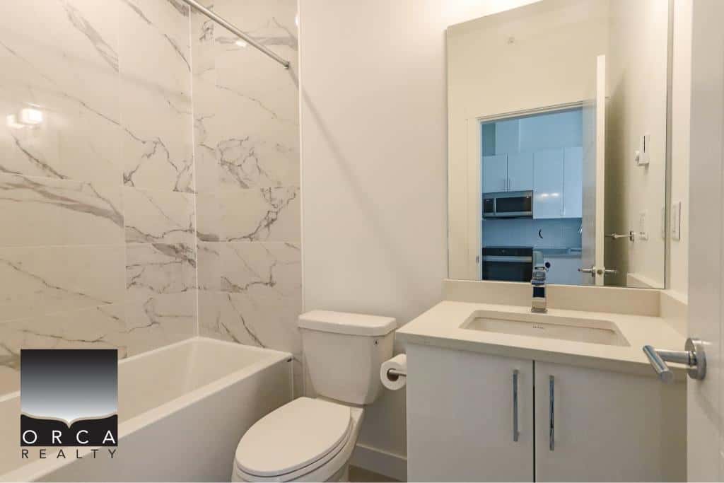 Modern bathroom with marble tile accents, white vanity, and contemporary fixtures, showcasing Ottawa real estate expertise with Orca Realty Inc.