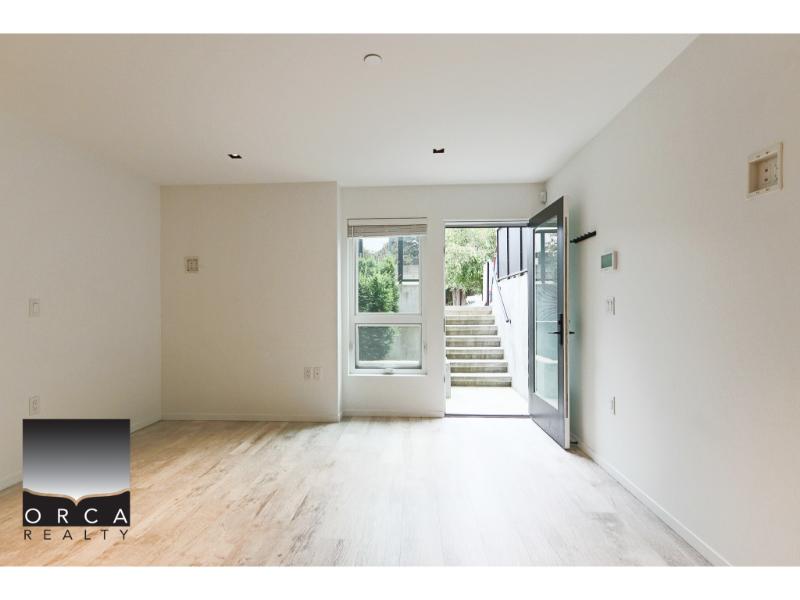 Bright vacant living room in a modern apartment with natural light and hardwood flooring, ideal for homebuyers in Vancouver and surrounding areas seeking real estate opportunities.