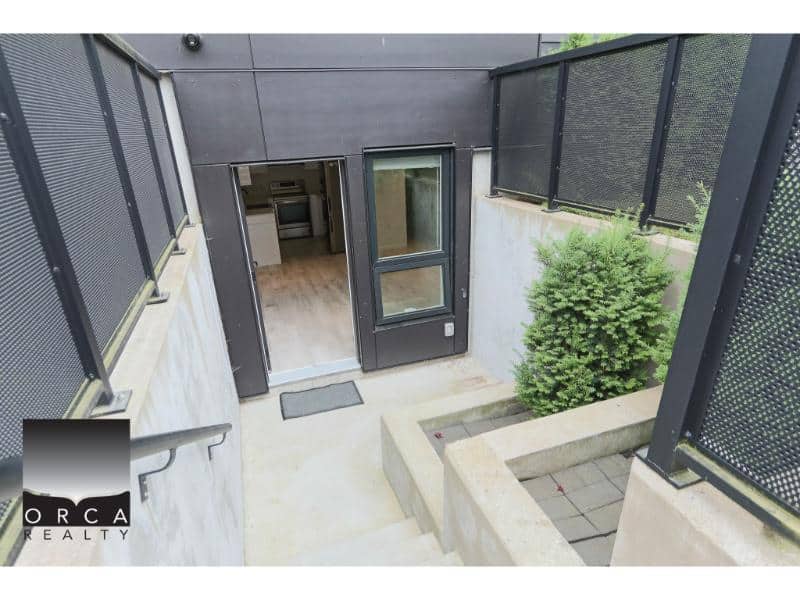 Modern townhouse entrance with black metal fencing and greenery, showcasing contemporary architecture and private outdoor space in a Vancouver area property.