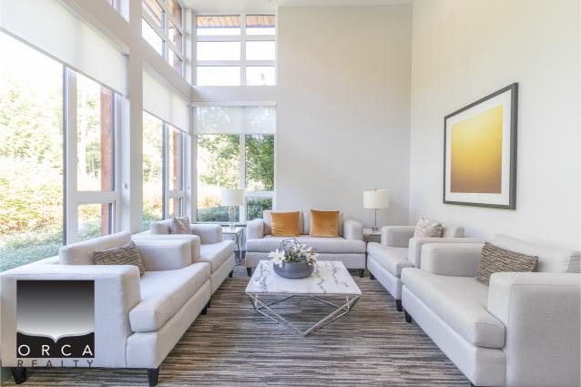 Bright modern living room with large windows, white sofas, and stylish decor, showcasing upscale Vancouver real estate with Orca Realty Inc.