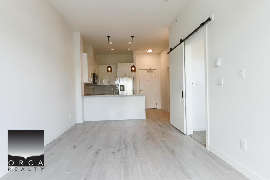 Bright modern open-concept living space with kitchen and sliding barn door, ideal for Vancouver housing market. Perfect for first-time homebuyers, renters, or investors in British Columbia.