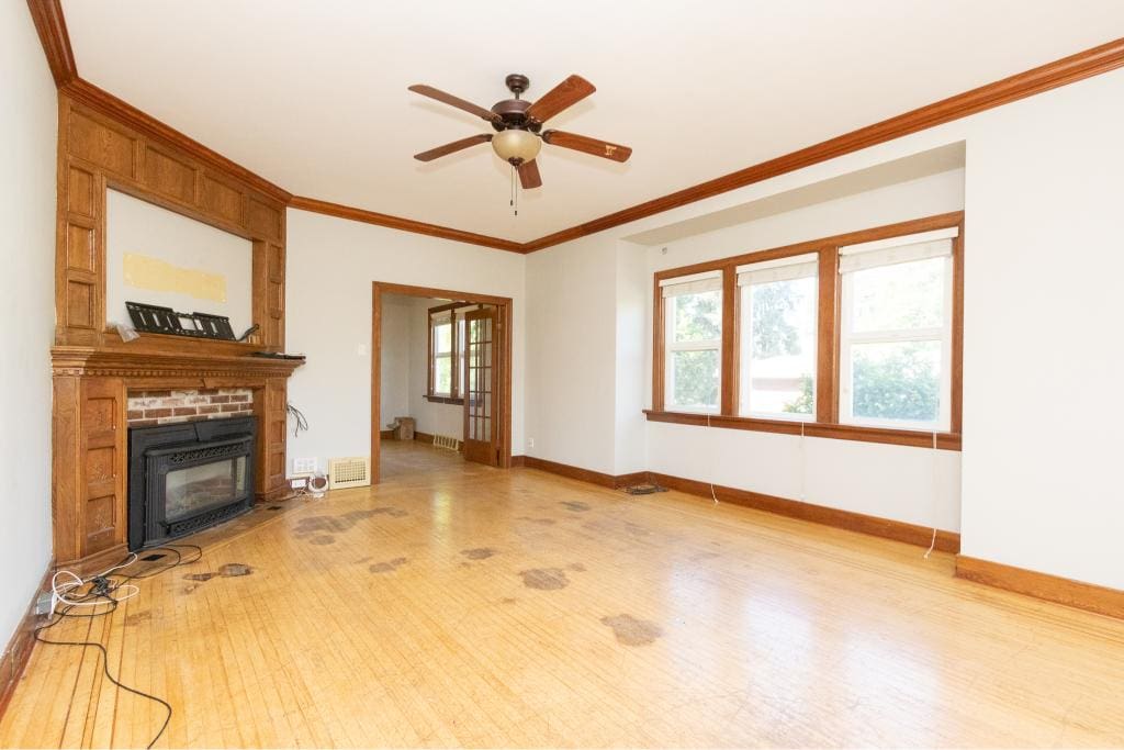 Spacious living room with hardwood floors, large windows, and a cozy fireplace, featuring classic wooden trim and natural light, ideal for Vancouver Island real estate.
