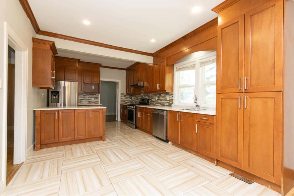 Bright, modern kitchen interior with rich wooden cabinets, stainless steel appliances, and tiled flooring; perfect for family living and entertaining.