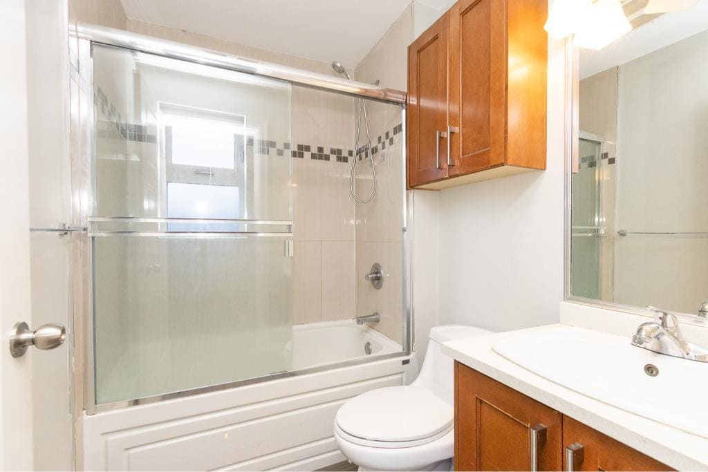 Bright modern bathroom with bathtub, shower, wooden cabinets, and white fixtures, ideal for Vancouver Island homes. Perfect for real estate listings showcasing functional interior spaces.
