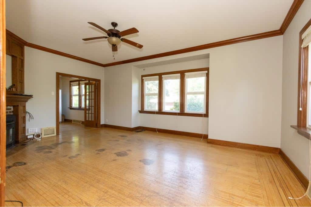 Bright spacious living room with hardwood floors, large windows allowing natural light, and classic wood trim, ideal for homebuyers seeking comfort and style in Orca Realty Inc. listings.
