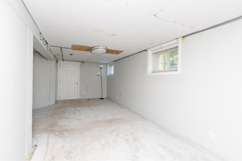 Unfinished basement interior with drywall and carpet flooring, natural light from small windows, part of a property listed by Orca Realty Inc. in Victoria, BC, showcasing potential home renovation space.