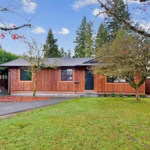 Cozy single-family home with a beautifully maintained front yard, surrounded by mature trees and a private wooden fence, ideal for Vancouver Island real estate investments.