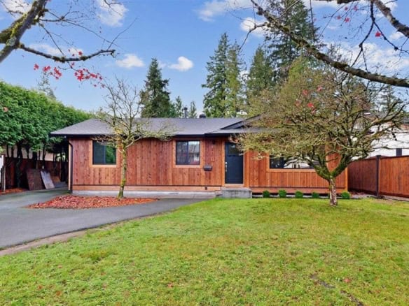 Cozy single-family home with a beautifully maintained front yard, surrounded by mature trees and a private wooden fence, ideal for Vancouver Island real estate investments.