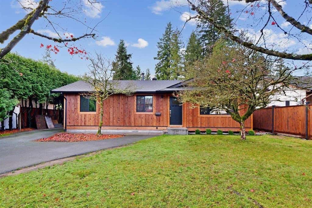 Cozy single-family home with a beautifully maintained front yard, surrounded by mature trees and a private wooden fence, ideal for Vancouver Island real estate investments.