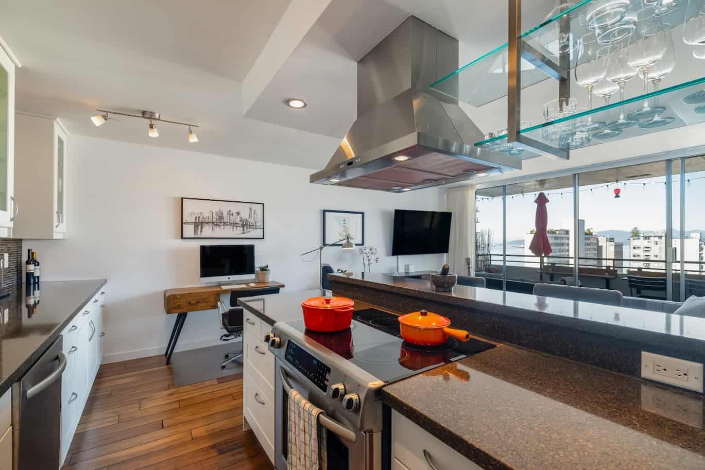 Bright modern kitchen with stainless steel appliances, open living space, and city views from the balcony in a Vancouver condo. Perfect for condo living and real estate investment.