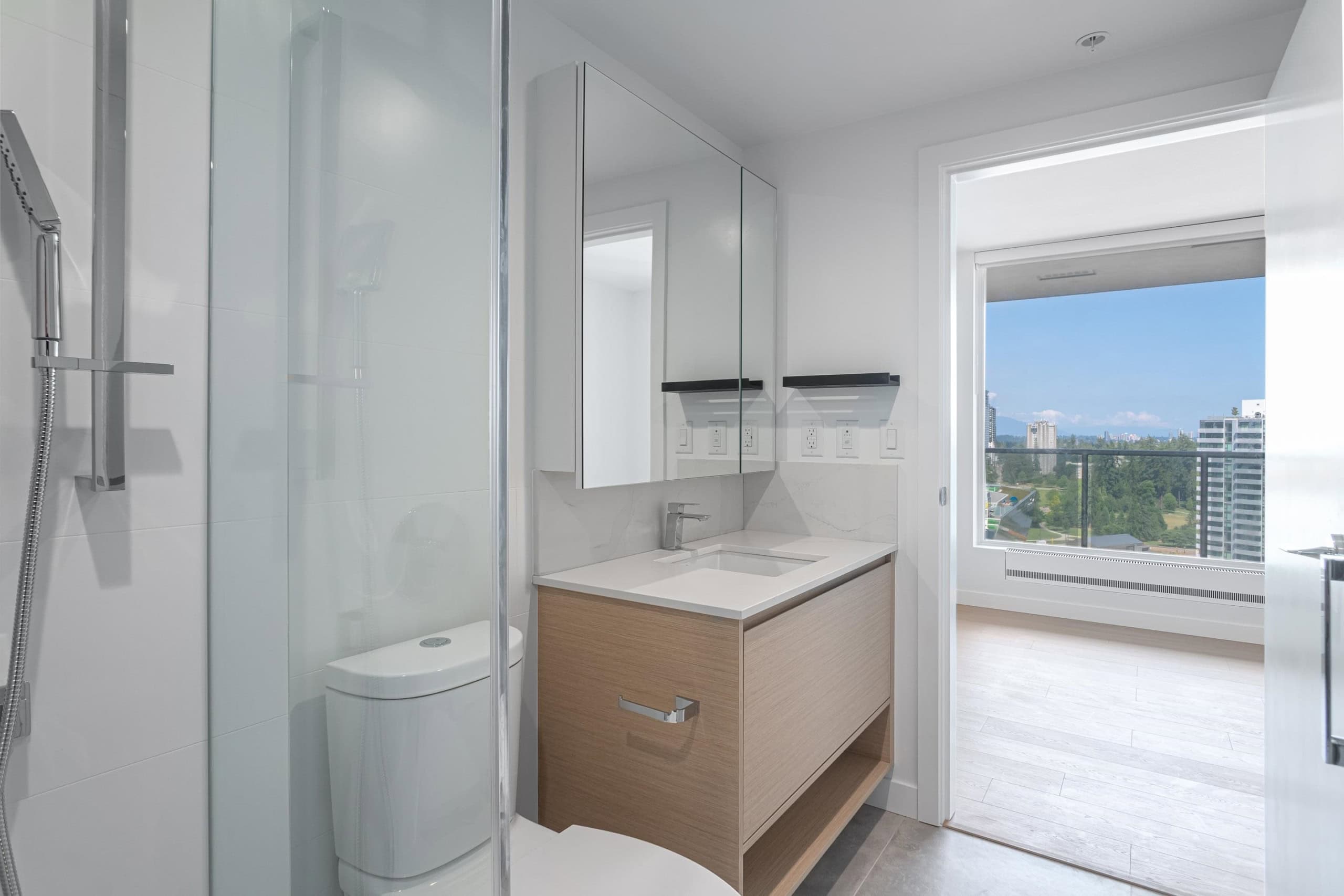 Modern bathroom with white tiles, minimalist vanity, and large window offering city views, perfect for upscale Vancouver real estate.