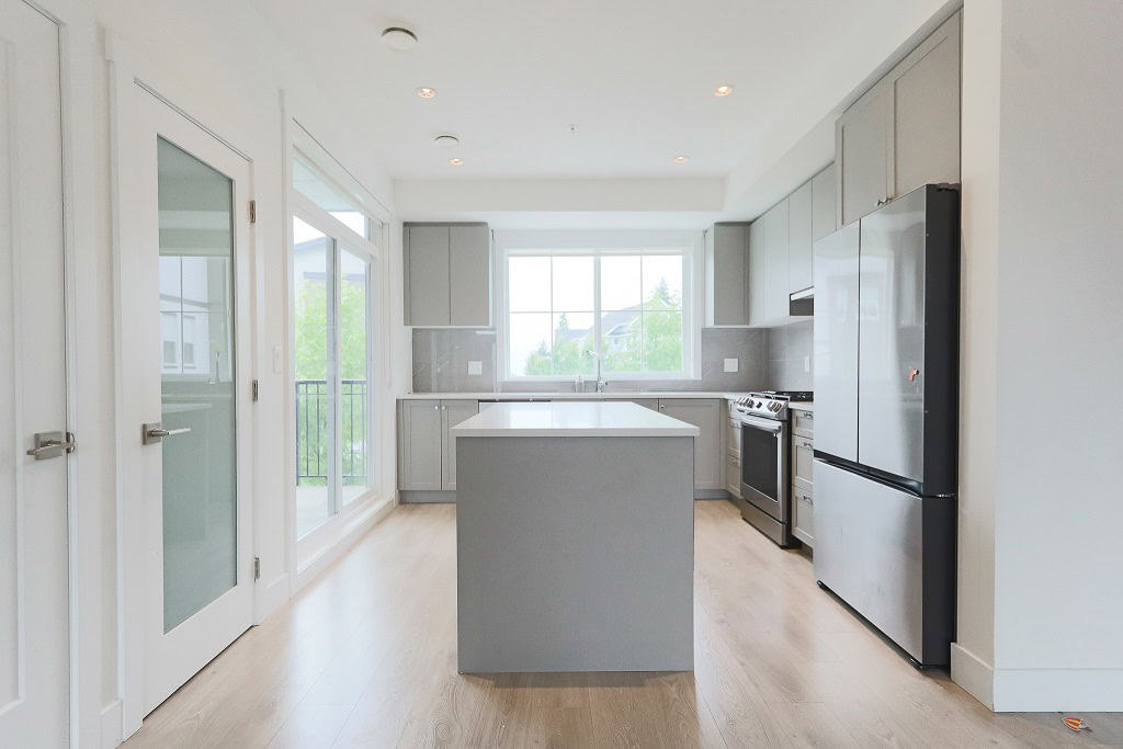 Bright modern kitchen with stainless steel appliances, grey cabinetry, and a central island in a contemporary home by Orca Realty Inc.