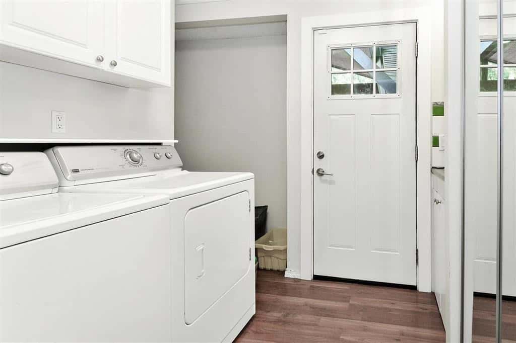 Washer and laundry room in a modern home, white appliances, wooden flooring, exterior door, laundry area with storage, Orca Realty Inc.