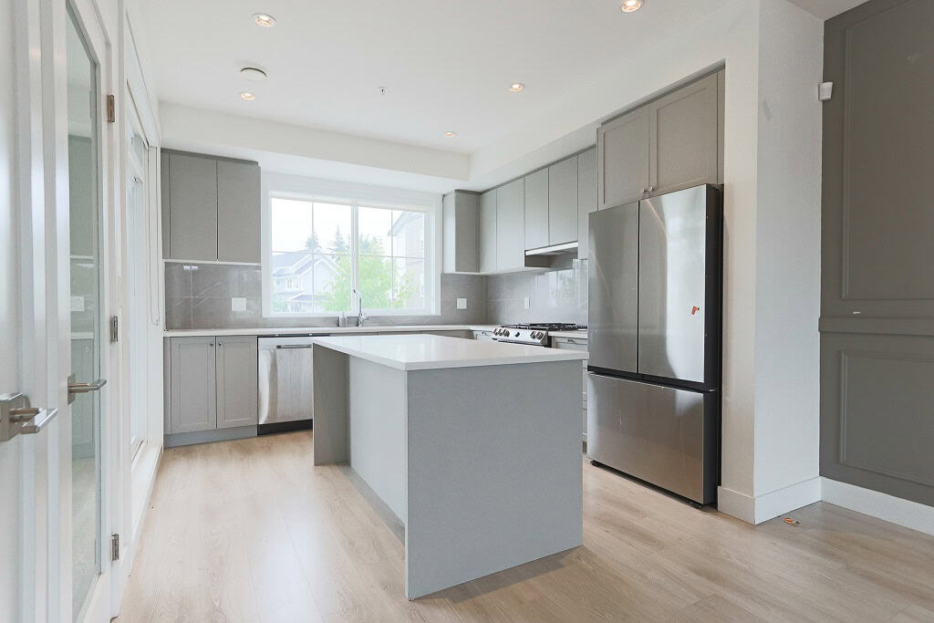 Sleek modern kitchen with grey cabinetry, stainless steel appliances, and a central island, ideal for Vancouver Island real estate.