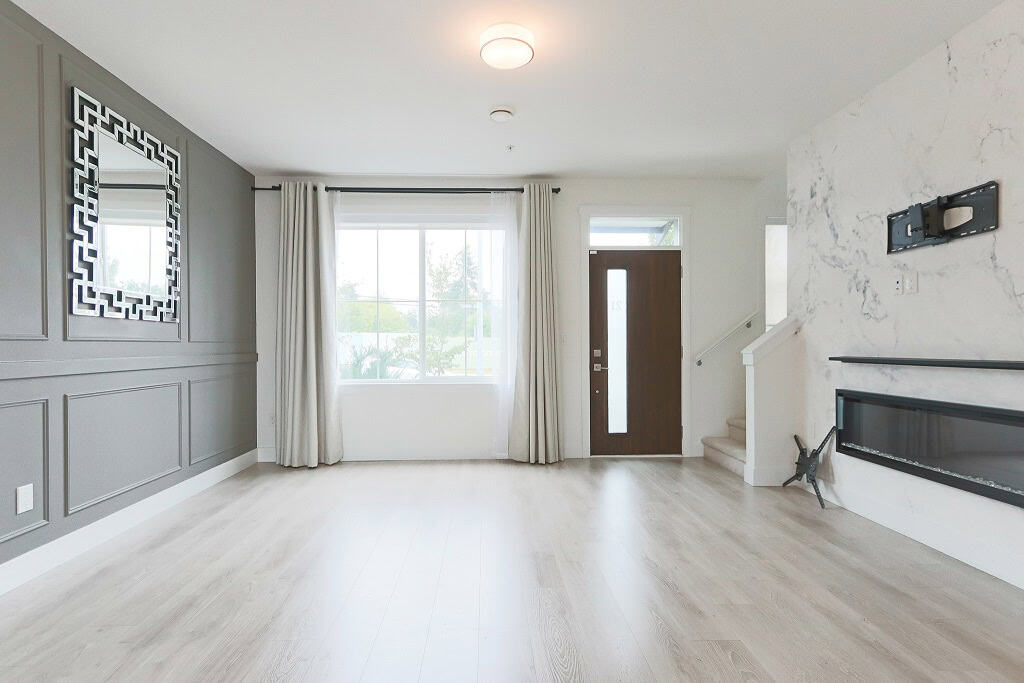 Bright living room with modern design, large window, elegant wall paneling, and contemporary fireplace, ideal for showcasing property features for Orca Realty listings.
