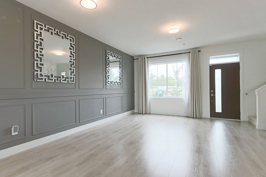 Modern living room interior with decorative mirrors and large window, in a property listed by Orca Realty Inc., showcasing contemporary decor and natural light in a home for sale in Canada.