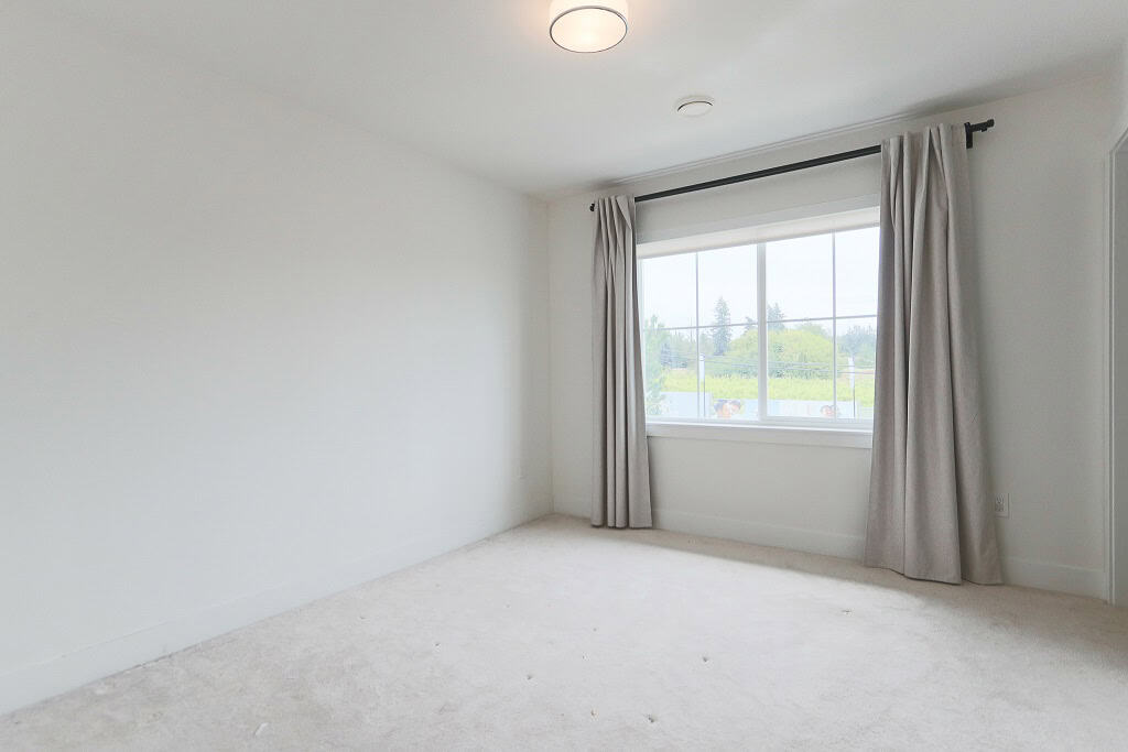 Bright, airy bedroom with large window and neutral decor, ideal for cozy living spaces in Surrey real estate. Perfect for families and homeowners seeking comfort and natural light.