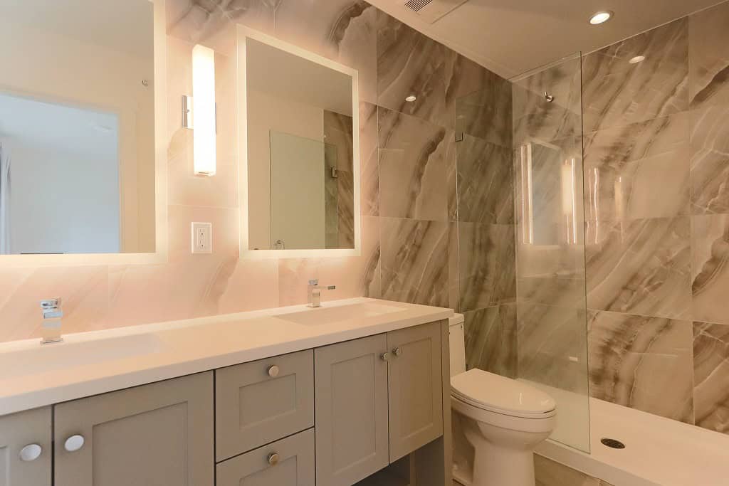 Modern bathroom with double vanity, elegant mirrors, and marble tile shower, showcasing luxury home features from Orca Realty Inc. in BC.