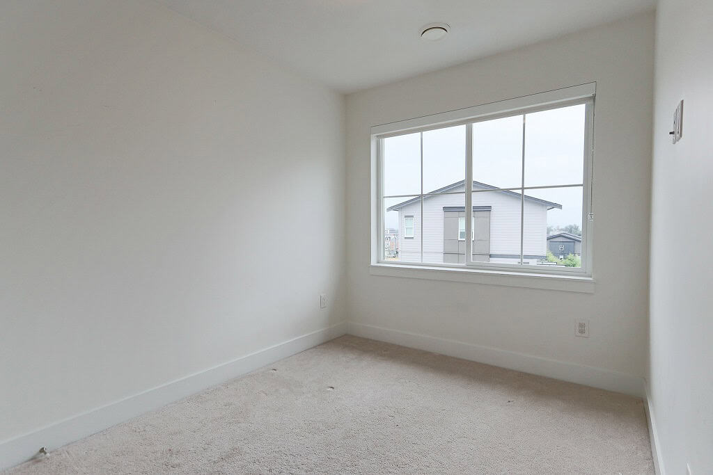 Bright empty bedroom with large window in a modern home, perfect for real estate listings, showcasing interior features, and appealing to homebuyers in Ontario.