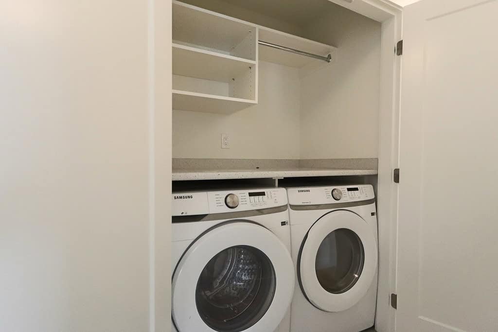 Samsung washer and dryer set in a bright laundry closet with shelving for storage, ideal for modern homes in Vancouver.