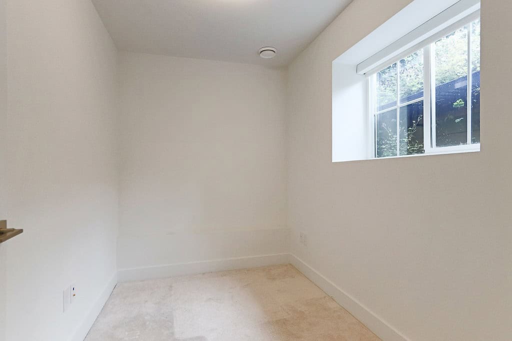Bright, empty room with white walls and a large window showcasing natural light, perfect for home staging or real estate listings in Victoria, BC.