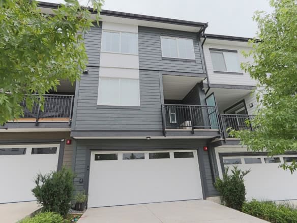 Contemporary multi-family townhouse with modern design, grey siding, spacious balconies, and attached garages, situated in a desirable neighbourhood - perfect for real estate investment or homeownership in BC.