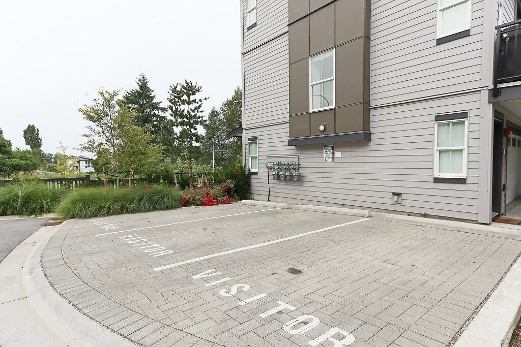 Modern residential apartment building with designated parking spots and landscaped surroundings, representing professional real estate services by Orca Realty Inc.